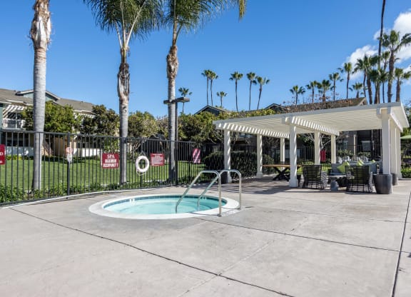 Goleta, CA Apartments Near UC Santa Barbara - Sumida Gardens - Spa beside Pergola with Patio Furniture, and Palm Trees.