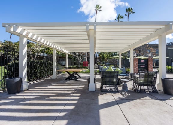 a covered patio with tables and chairs under a white roof