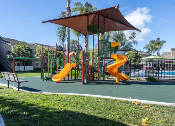 a playground with two slides and an umbrella in a park
