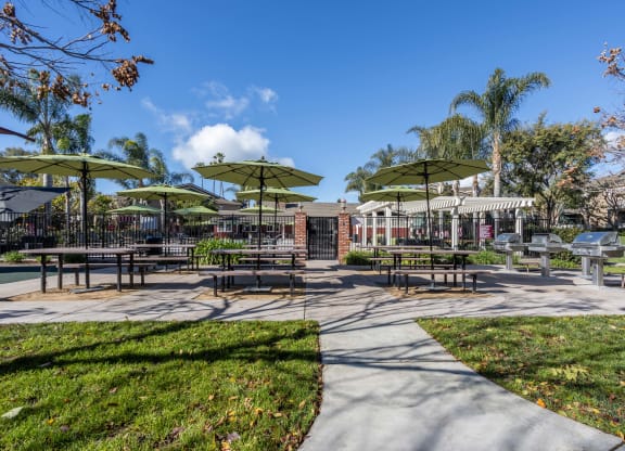 a picnic area with tables and umbrellas in a park