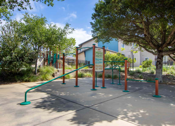 a playground in a park with trees and a building