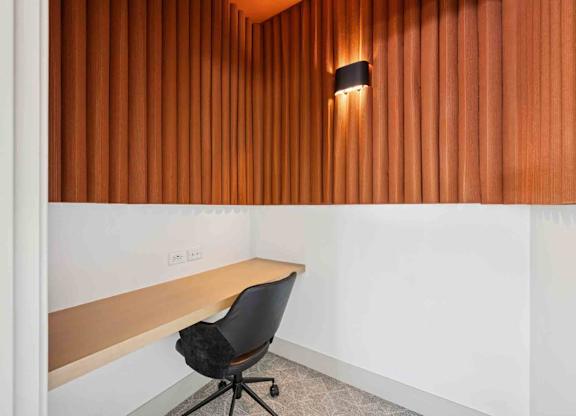 A black chair is in front of a wooden wall.
