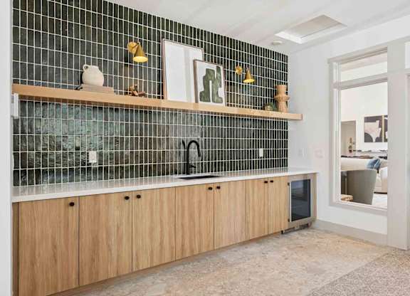 A kitchen with wooden cabinets and a black tile backsplash.