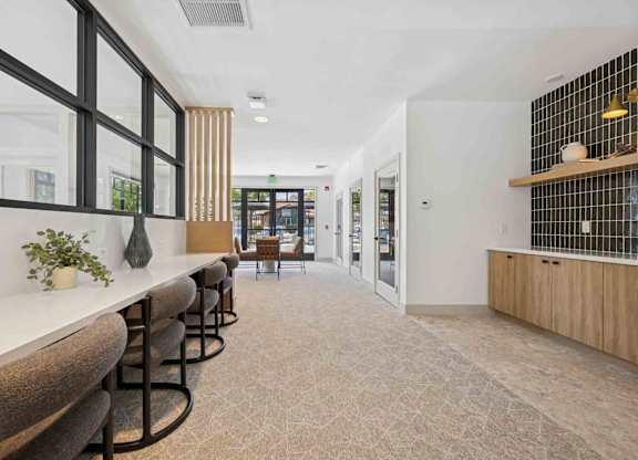 A long white table with brown chairs is in a room with a tiled wall.