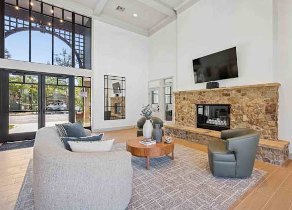 A living room with a stone fireplace and a flat screen TV mounted on the wall.