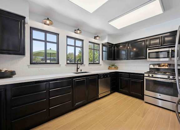 A modern kitchen with black cabinets and stainless steel appliances.