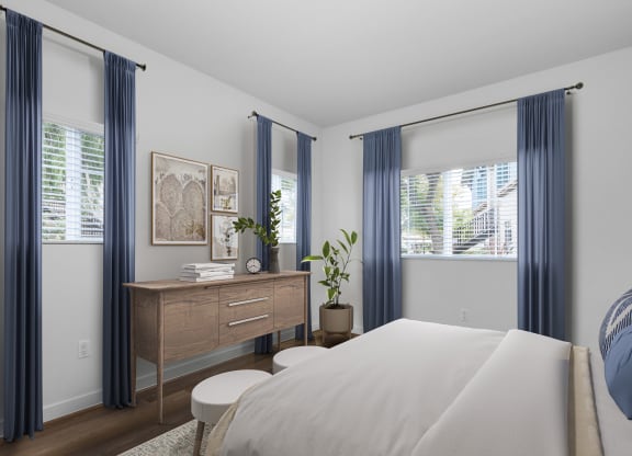 a bedroom with a large bed and two windows with blue curtains