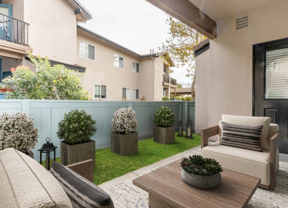 a patio with a couch and a table and plants