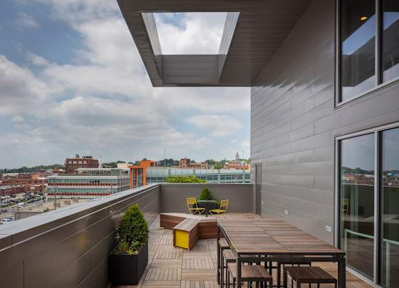 A balcony with a table and chairs overlooking a cityscape.