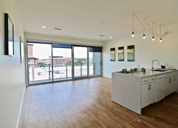 A kitchen with a white counter and cabinets with a view of a parking lot outside.