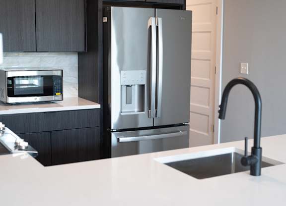 A modern kitchen with a stainless steel refrigerator and a white countertop.