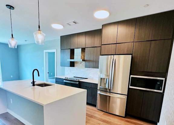 A modern kitchen with a white island and wooden floors.