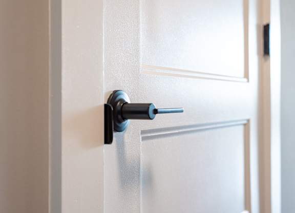 A door handle with a keyhole is on a white door.