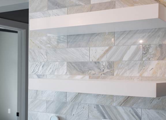 A marble wall with a white shelf above it.