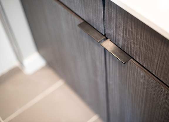 A close up of a drawer handle on a wooden cabinet.