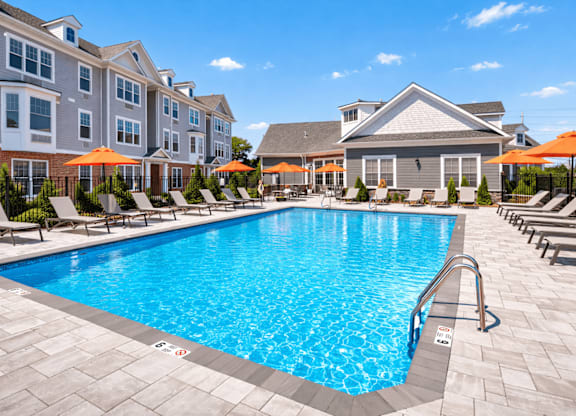 A large swimming pool surrounded by lounge chairs and umbrellas.