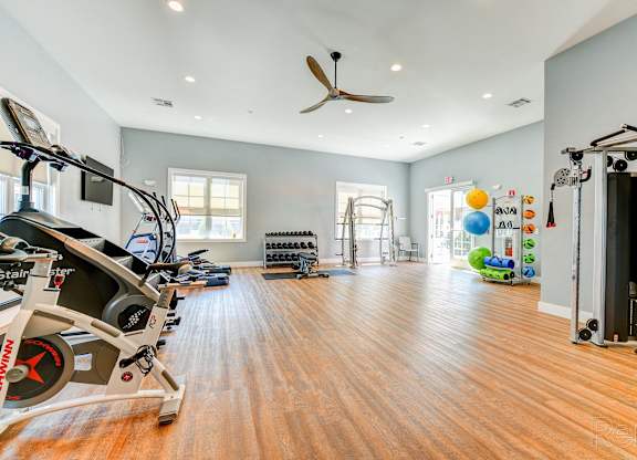 A spacious gym with a variety of equipment and a wooden floor.