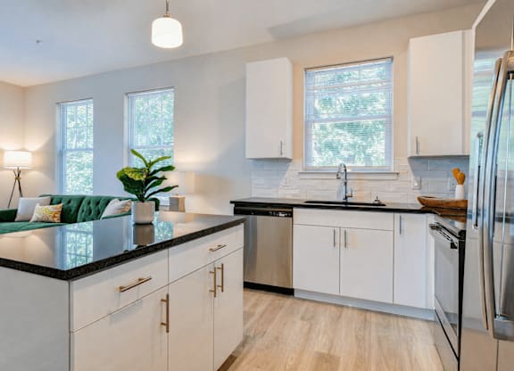 A modern kitchen with white cabinets and a black countertop.