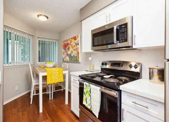 a kitchen with a stove and microwave and a table and chairs at The Villages of Banyan Grove, Florida