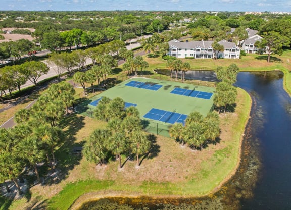 a tennis court with a house on the side of a lake at The Villages of Banyan Grove, Florida, 33436