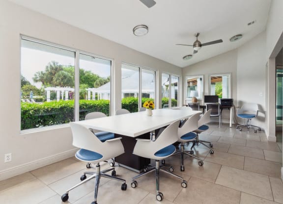 a conference room with a white table and chairs and windows at The Villages of Banyan Grove, Boynton Beach, 33436