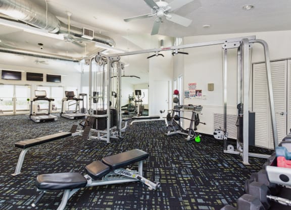 a gym with cardio equipment on the floor and a ceiling fan at The Villages of Banyan Grove, Boynton Beach, FL