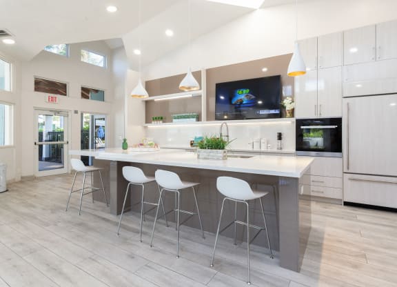 a kitchen with white cabinets and a large island with three stools at The Villages of Banyan Grove, Boynton Beach