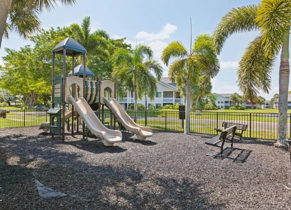 playground with slides and picnic tables in front of a house at The Villages of Banyan Grove, Boynton Beach