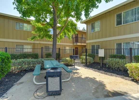 Asbury Place community picnic table and trash can outside  in a courtyard area