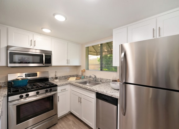 an updated kitchen with stainless steel appliances and white cabinets