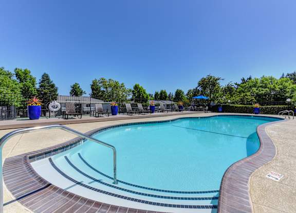 Swimming Pool entrance with bright blue gardening pots along the fence-line with plants in the distance.at The Renaissance Apartments, California