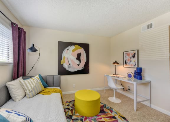 Bedroom with Daybed , White Desk, White Chair, Colorful Rug and Yellow Foot Stool at Silverstone Apartments, California