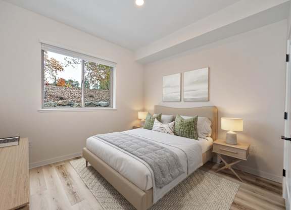 A bedroom with a large bed and a window overlooking a tree-covered landscape.