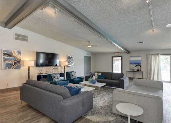 Community Clubhouse Lounge Area with Harwood inspired flooring through out with gray couches and Flat Screen Television at The Renaissance Apartments, Citrus Heights, CA 95610
