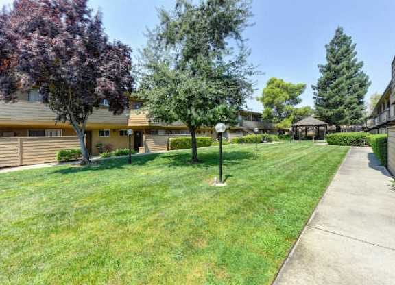 Green Outdoors Walkways with Grass, Trees and Apartment Exteriors  at Olympus Park Apartments, Roseville, 95661