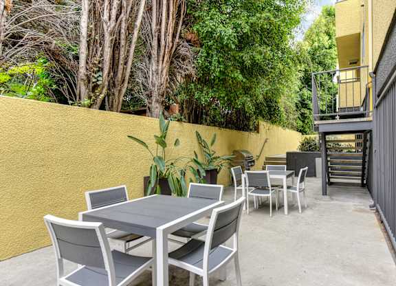 Community BBQ Area with Grill, Picnic Tables, Yellow Wall and Cement Floor at Croft Plaza Apartments, West Hollywood, CA