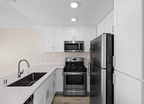 A modern kitchen with a sink, stove, and refrigerator.