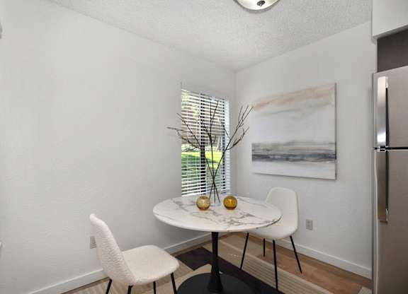 a small dining room with two white chairs and a marble table with two vases on it at Fountains of Fair Oaks, Fair Oaks