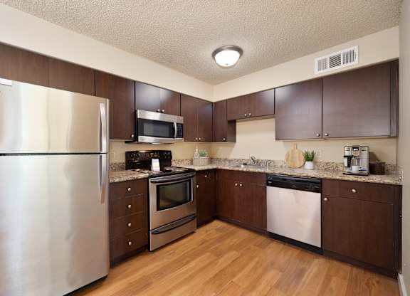 a kitchen with stainless steel appliances and wooden cabinets at Fountains of Fair Oaks, California