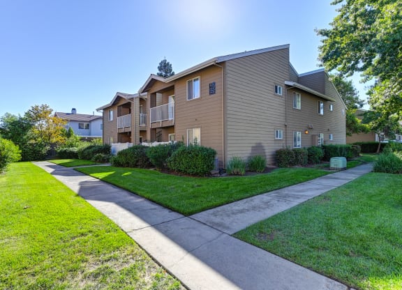 View of a two story apartment building at Hasting Park with a sidewalk and lawn