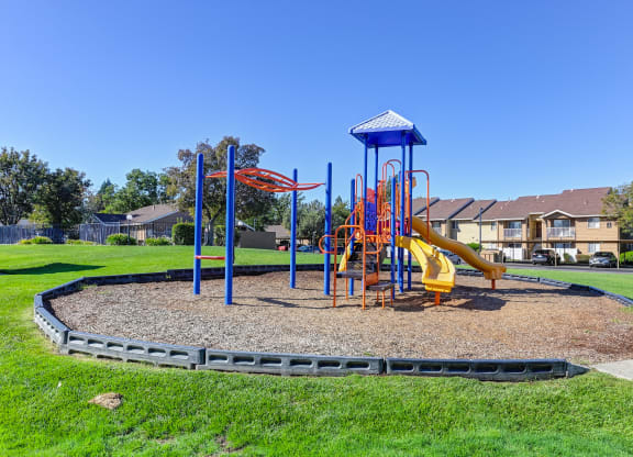 Playground on-site with slides and monkey bars surrounded by large grassy area