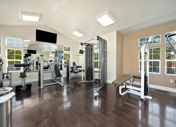 a gym with weights machines and a TV at Hidden Oaks Apartments, Citrus Heights, CA