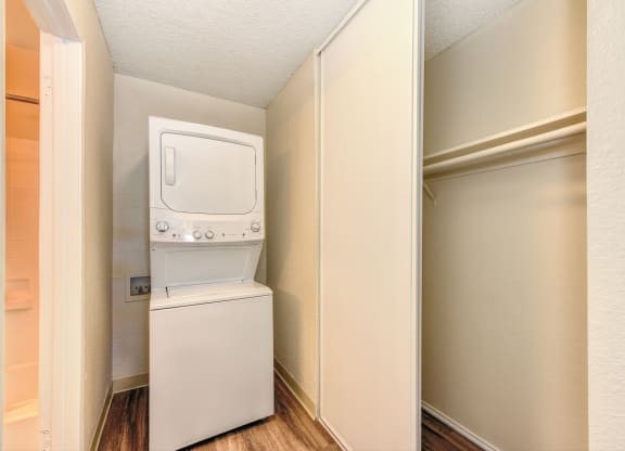 Stackable washer and dryer inside apartment with closet to the right and Hardwood Inspired Floors at Renaissance Park Apartments, Davis