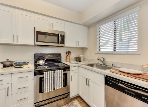 Kitchen with White Cabinets, Oven, Microwave, Window and Dishwasher at Silverstone Apartments, Davis, California