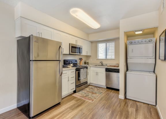Kitchen with Washer/Dryer , Hardwood Inspired Floor, Refrigerator and White Cabinets at Silverstone Apartments, Davis