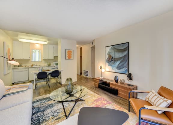 Living Room with View of Dining Area, Hardwood Inspired Floor, Colorful Rug, Brown Chair and White Sofa at Renaissance Park Apartments, Davis, CA