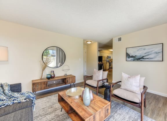 Living room with two tone paint,  Hardwood Inspired Floor, Gray/White Rug, Gray Sofa and Round Mirror at Silverstone Apartments, Davis, CA, 95618