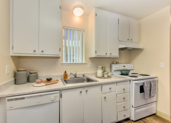 Kitchen with white cabinets and appliances, including dishwasher and stove/oven. at Renaissance Park Apartments, Davis ,36305