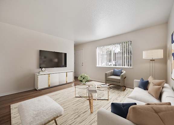 A living room with a white sofa, a white chair, a wooden coffee table, and a television on a cabinet.