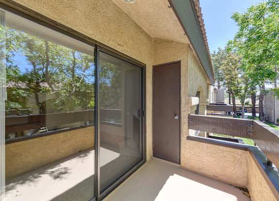 A patio with a sliding glass door and a brown door.